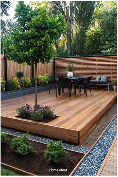 a wooden deck surrounded by plants and trees in the middle of a garden with seating area