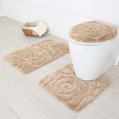 two bathroom rugs on the floor next to a toilet