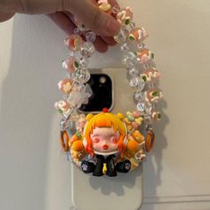 a cell phone holder with a doll hanging from it's side on a wall