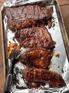 bbq ribs and barbecue tongs sitting on top of tin foil