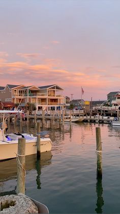 several boats are docked in the water near houses and buildings at sunset or sunrise time