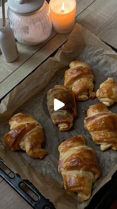 there are many croissants that are on the table next to a candle