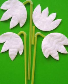 three white flowers made out of paper on a green surface