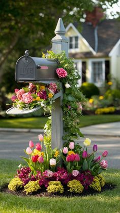 a mailbox is decorated with flowers and greenery in front of a house on a suburban street