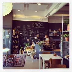 the interior of a coffee shop with chalkboard writing on the wall and plants in pots