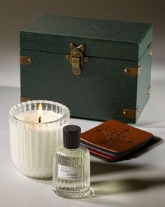 a candle and some books next to a green box on a white table with a book