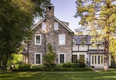 a large stone house surrounded by trees and grass