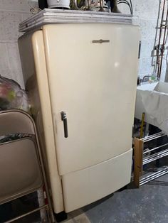 an old white refrigerator sitting in a garage