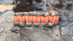 an orange and green paracorine bracelet sitting on top of a rock