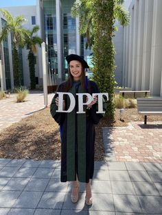 a woman in graduation gown holding up a sign that says do it with her hands