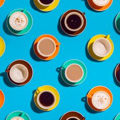 several cups of coffee are lined up on a blue surface