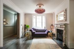 a living room filled with furniture and a chandelier hanging from the ceiling over a fire place