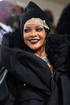 a woman wearing a black hat and dress with jewels on her head, posing for the camera