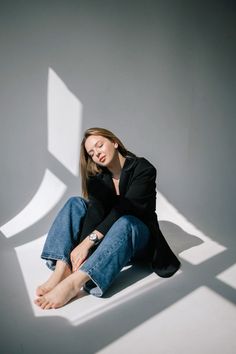 a woman is sitting on the floor with her hands in her pockets and looking down