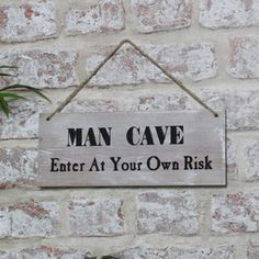 a man cave sign hanging on the side of a brick wall with a plant in it