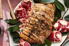 a plate with meat, pomegranates and leaves on it