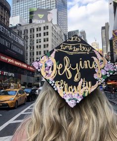 a woman wearing a black graduation cap with gold lettering