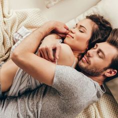 a man and woman laying in bed with their heads touching each other's foreheads