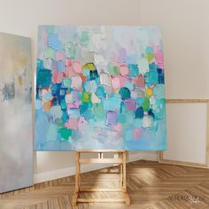 an abstract painting is on display in a room with wooden flooring and white walls