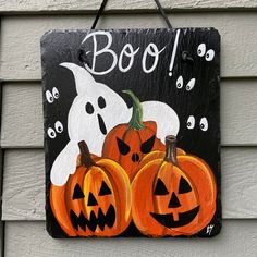 a wooden sign with three pumpkins and ghost faces on it that says booj