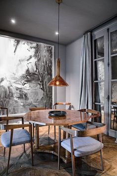 a dining room table with chairs and a painting on the wall