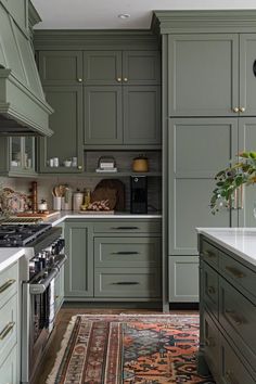 a kitchen with green cabinets and an area rug in front of the stove top oven