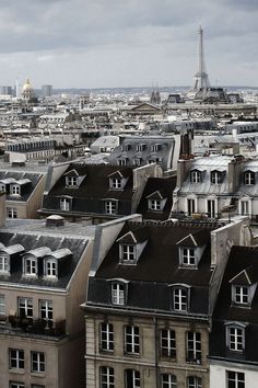 an aerial view of the roofs of buildings in paris, with the eiffel tower in the distance