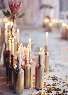 there are many bottles with candles in them on the table