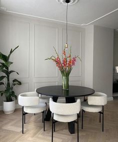 a black table with four white chairs around it and a potted plant in the middle