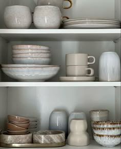 the shelves are filled with dishes and cups