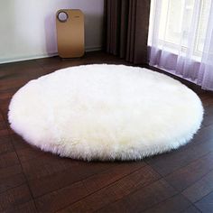 a large white round rug on top of a hard wood floor next to a window