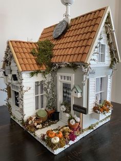 a doll house is decorated with fake flowers and greenery on the roof, along with other decorations