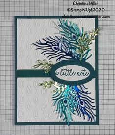 a close up of a greeting card with blue and green feathers on it, which reads little note