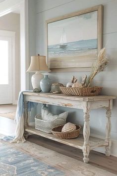 a white table with baskets and vases on top of it next to a painting