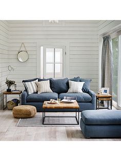 a living room with blue couches and pillows on the floor next to a coffee table