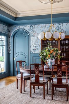 an elegant dining room with blue walls and wood furniture, along with floral wallpaper