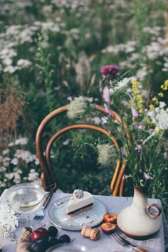 a table topped with plates and vases filled with flowers on top of a field