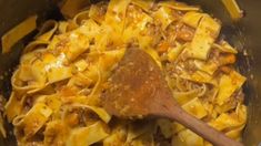 a wooden spoon in a pot filled with pasta