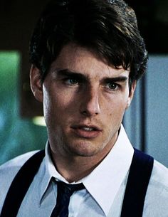 a young man wearing suspenders and a white shirt is looking at the camera with an intense look on his face