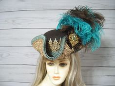 Gorgeous ladies brown woolen blend pirate/tricorn hat with golden venise lace and trim, small glass turquoise rhinestones hand placed on each point of the lace, a brown satin cocarde with a sparkly golden jewel and brown and turquoise ostrich feathers. This hat is about 22 1/2" for the inside circumference with a built-in hat adjuster ribbon. I cannot make the circumference of the hat bigger. Please measure your head so you know if this will fit you. Check out all the pirate hats and other style Tricorn Hat, Fair Outfits, Pirate Hat, Pirate Hats, Pirate Woman, Brown Satin, Steampunk Design, Pirate Costume, Jack Sparrow