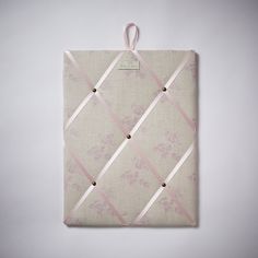 a pink and white wall hanging with ribbon