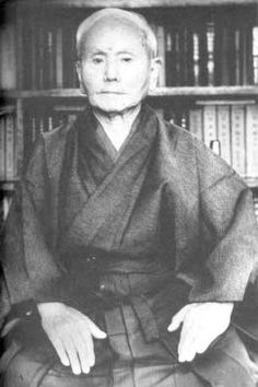 an old photo of a man sitting in front of bookshelves