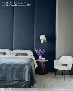 a bedroom with a blue headboard and white bedding, along with a chair