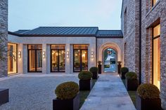 an entrance to a modern home with stone walls and large planters on either side