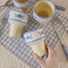 three cups of tea are sitting on a table with silverware and utensils