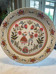 a decorative plate on a table in front of a window