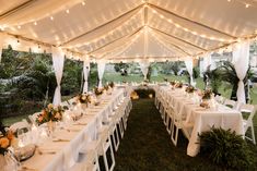 a large tent with tables and chairs set up for an outdoor wedding reception at night