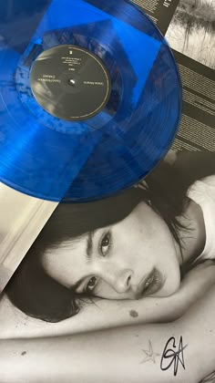 a blue record sitting on top of a table next to a woman's face