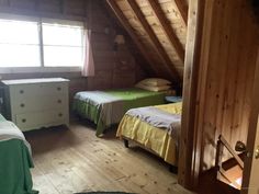 there are two beds in the attic with green and yellow sheets on them next to each other