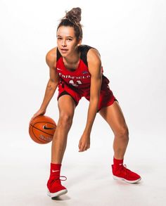 a young woman holding a basketball in her right hand and wearing red sneakers on the other side